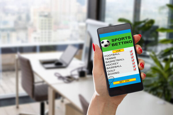 woman holding a mobile phone with sports betting website in the screen.