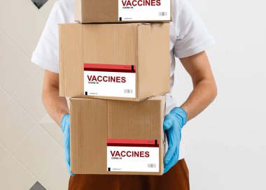 Adam aşı kutusunu beyaz arka planda tutuyor.