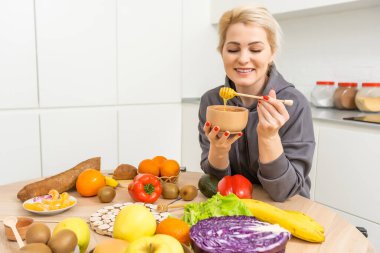 Güzel bir kadın yemek pişiriyor ve mutfakta eğleniyor. Kız mutfakta bal ile sağlıklı yemek pişiriyor.