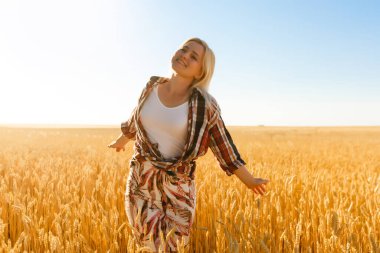 Batan güneşin arka planındaki buğday tarlasında bir kadın.