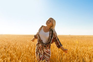 Batan güneşin arka planındaki buğday tarlasında bir kadın.