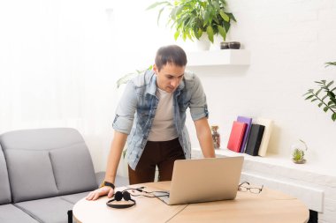Adam evdeki masada dizüstü bilgisayar kullanıyor