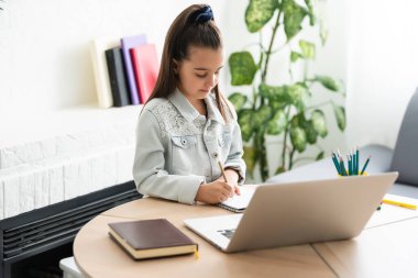 Çocuklar, eğitim ve uzak öğrenim konsepti, evde dizüstü bilgisayarı olan küçük kız öğrenci