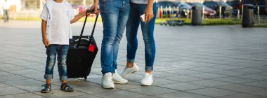 Yolculuk başlasın. Oğullarıyla birlikte havaalanında ellerinde bavullarla yürüyen şirin bir çift portresi.