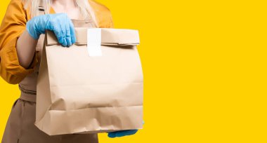 Coronavirus salgını sırasında plastik restoranda organik yemek hazırlayan genç bir kadın mutfakta online dağıtım servisi için yemek pişiriyor.