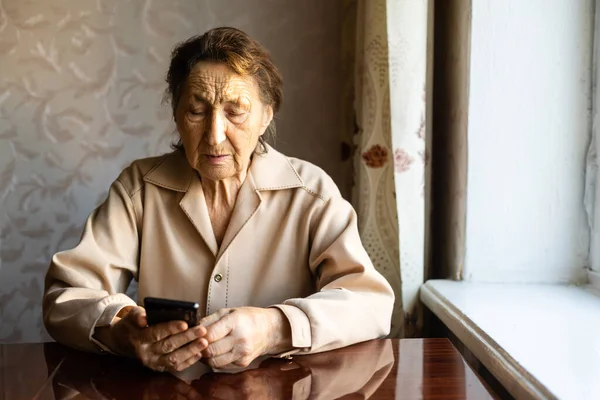 Mulher muito velha usar um smartphone em casa. — Fotografia de Stock
