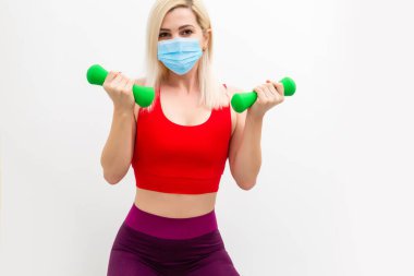 Genç spor kadın antrenmanı ve tek kullanımlık tıbbi maske takıyor. TRX kavramı beyaz arkaplanda izole edildi.