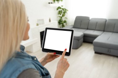 Akıllı ev kavramı. Genç bir kadın tablet üzerinde akıllı ev uygulaması kullanıyor.