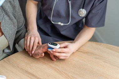 Doktor hemoglobin seviyesini ölçüyor. Parmak nabız oksimetresinin kullanımı gösteriliyor