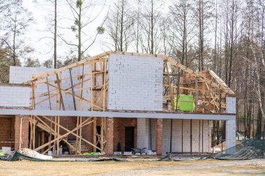 İnşaat alanındaki büyük pencereli beyaz bloklardan yapılmış bina cephesi