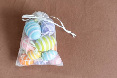 Yaratıcı bir şekilde Paskalya yumurtalarını gri arka planda bir çantaya boyamış. Düz yat, boşluğu kopyala.