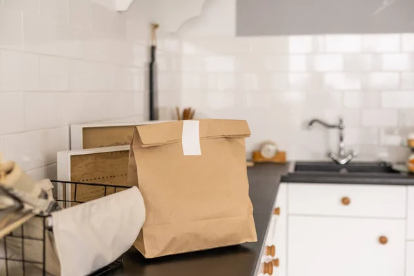 Εικόνα φόντου από χάρτινη τσάντα χειροτεχνίας σε ξύλινο τραπέζι σε λευκό εσωτερικό κουζίνας με ετικέτα Βιολογικά Τρόφιμα, υπηρεσία παράδοσης τροφίμων, αντιγραφή χώρου. — Φωτογραφία Αρχείου