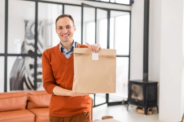 Cheerful delivery man. Happy young courier holding a delivery package. — Stock Photo, Image