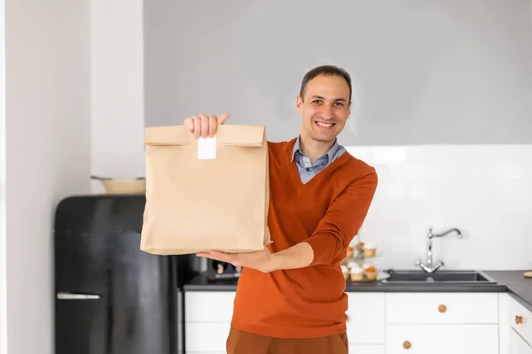 Un repartidor alegre. Feliz joven mensajero sosteniendo un paquete de entrega. —  Fotos de Stock