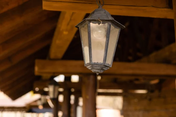 Uma lâmpada preta vintage sob o teto em uma fazenda de madeira. Lâmpada à moda antiga. Espaço de cópia. — Fotografia de Stock