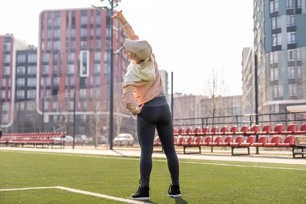 Deporte. Chica de fitness haciendo ejercicio de estiramiento. Moda mujer deportiva con fuerte entrenamiento corporal muscular. Ajuste de estiramiento femenino en el estadio al aire libre. —  Fotos de Stock