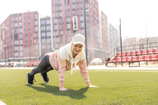 Fitness e esportes. Jovem mulher fazendo alongamento no estádio — Fotografia de Stock