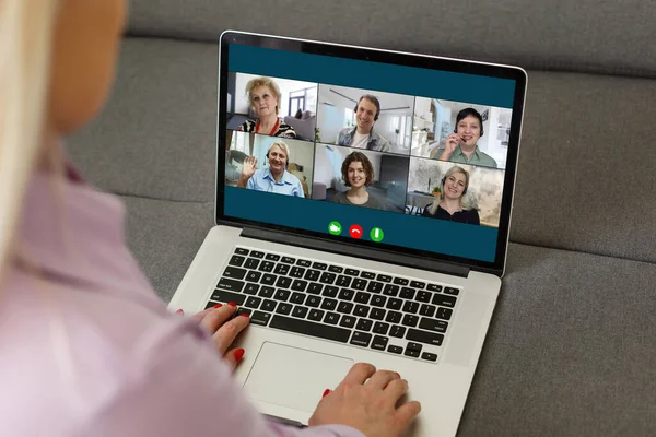 職場のデスクに座っている女性の肩越しに見るコンピュータ画面では、ビデオ会議の交渉活動に関わる多くの多様な人々のコラージュ、現代のアプリ技術使用の概念 — ストック写真