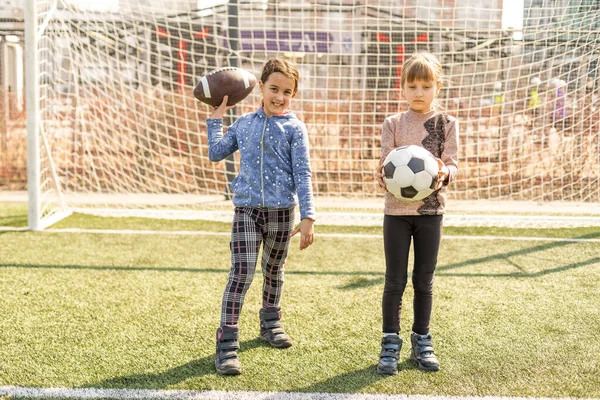 Mała drużyna piłkarska: małe dziewczynki z piłką nożną na boisku piłkarskim. — Zdjęcie stockowe
