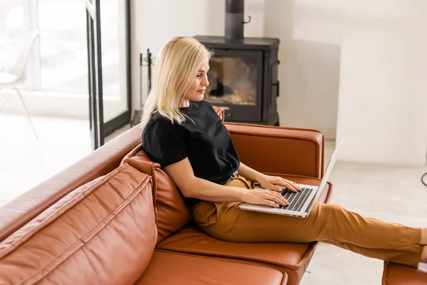 Trabalho remoto em casa, freelance durante a quarentena covid-19. Senhora sorrindo sentado e trabalhando no laptop em acolhedor interior da sala de estar, espaço livre — Fotografia de Stock