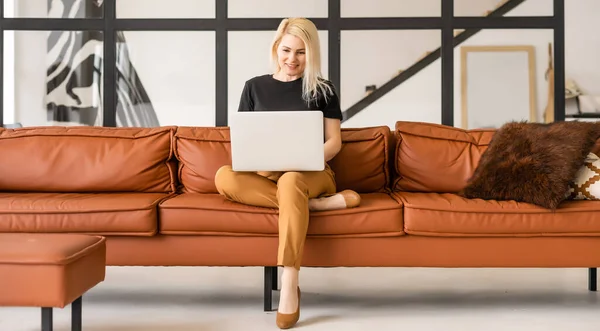 Feliz mulher bonita casual trabalhando em um laptop sentado na casa. — Fotografia de Stock