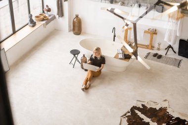 Genç ve güzel bir kadın evde dizüstü bilgisayar kullanıyor.