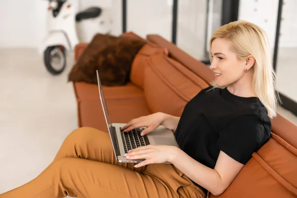 Fernarbeit zu Hause, freiberuflich während der covid-19 Quarantäne. Lächelnde Dame sitzt und arbeitet am Laptop in gemütlicher Wohnzimmereinrichtung, freier Raum — Stockfoto