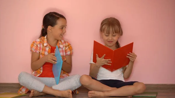 A kedves kislányok könyvet olvasnak. Az oktatás fogalma. Rózsaszín alapon elkülönítve — Stock Fotó