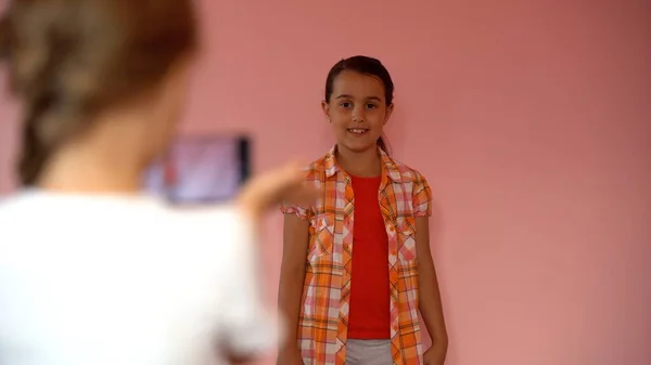 Две маленькие девочки фотографируются со смартфоном — стоковое фото