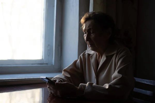 Пожилая женщина со смартфоном дома — стоковое фото