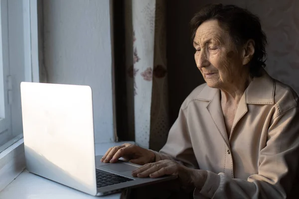 Mulher sênior feliz sentada com sua neta olhando para laptop fazendo chamada de vídeo. Mulher madura conversando com webcam, fazendo chat online em casa durante o auto-isolamento. Tempo de família durante Corona — Fotografia de Stock