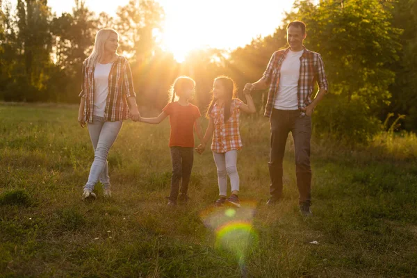 Mutlu aile tarlada yürüyor ve gün batımını seyrediyor. — Stok fotoğraf