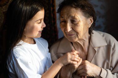 Küçük bir kız bebek ve çok yaşlı bir kadın. Küçük çocuk büyükannesine sarılıyor. Torunum.