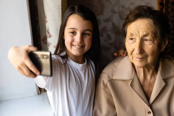 Granny and granddaughter. A cute little girl shows her grandmother a smartphone. — Stock Photo, Image