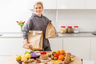 Elinde teslimat paketleriyle gülümseyen genç bir kadın.