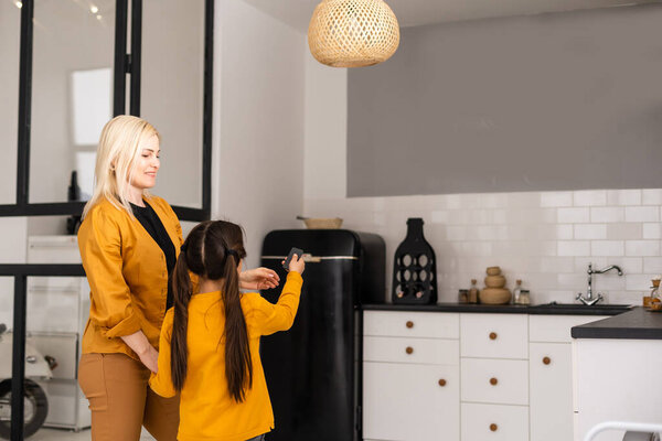 Молодая счастливая женщина держит пульт дистанционного управления кондиционер в доме