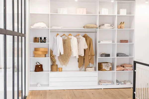Vêtements suspendus sur rail dans une armoire blanche avec boîte et chaussures — Photo