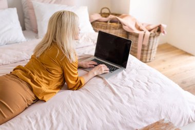 Uzaktan kumandalı ev işi, karantina sırasında serbest çalışma. Gülümseyen bayan rahat oturma odasında dizüstü bilgisayarda oturuyor ve çalışıyor.