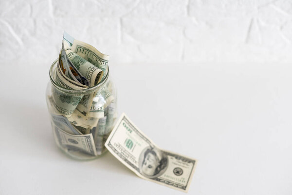 Много долларов банкноты в стеклянную банку изолированы на белом фоне