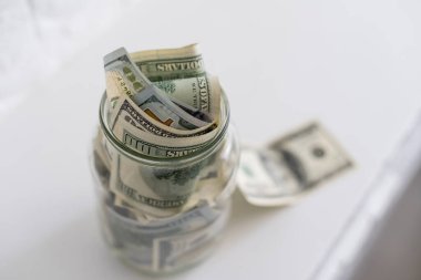 Beyaz arka planda izole edilmiş cam bir kavanozdaki banknotlar.