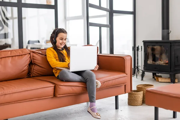 Kind online. Ein kleines Mädchen kommuniziert mit einem Laptop-Videochat, während es zu Hause am Laptop sitzt — Stockfoto