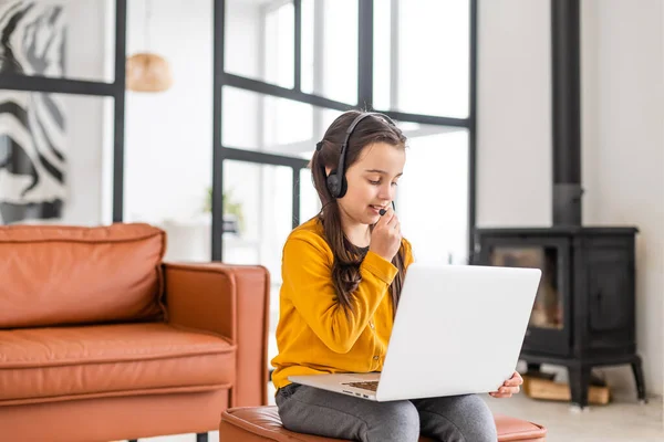 Az okos kislány elvégzi a házi feladatot a nappaliban. Ül és használ Laptop. — Stock Fotó