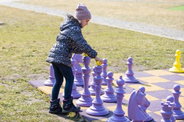 Küçük kız büyük satranç oynuyor.