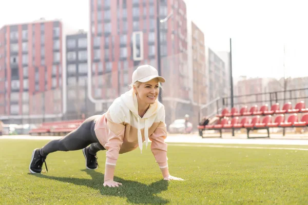 Fitness e esportes. Jovem mulher fazendo alongamento no estádio — Fotografia de Stock