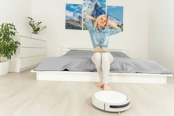 Robotic dammsugare städa rummet medan kvinnan vilar — Stockfoto