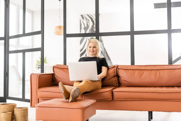 Boldog alkalmi szép nő dolgozik egy laptop ül a házban. — Stock Fotó