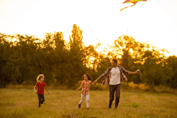 Feliz familia padre e hija correr con una cometa en el prado — Foto de Stock