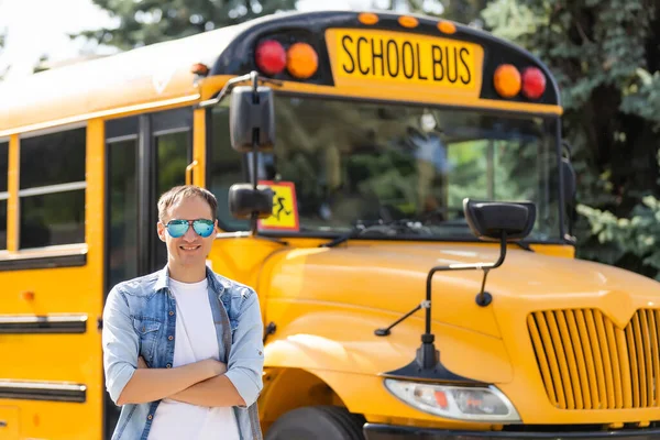 Portret van een lachende leraar in de buurt van schoolbus — Stockfoto