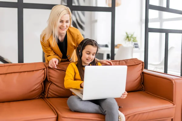 온라인 쇼핑이나 결제 개념. 어머니는 집에서 노트북을 사용하여 딸을 가르친다. 소파에 앉아서 — 스톡 사진