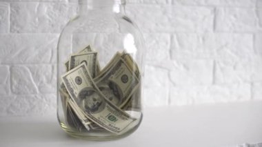 Tasarruf kavanozuna beyaz etiketli bir dolar koyarak.